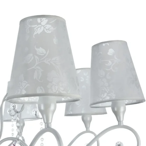 Серия выполнена в классическом стиле. В дизайне люстр и бра сделан легкий цветовой акцент на цепочки из мелких бусин и прозрачные розовые кристаллы. Торшер и настольная лампа имеют строгий и лаконичный дизайн. Все изделия серии, кроме бра, в основании дек